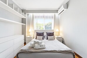 Une chambre d’hôtel avec un lit, deux tables de chevet, une fenêtre avec des rideaux et un escalier.