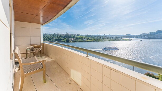 En balkon med udsigt over en flod, en båd og en bro.