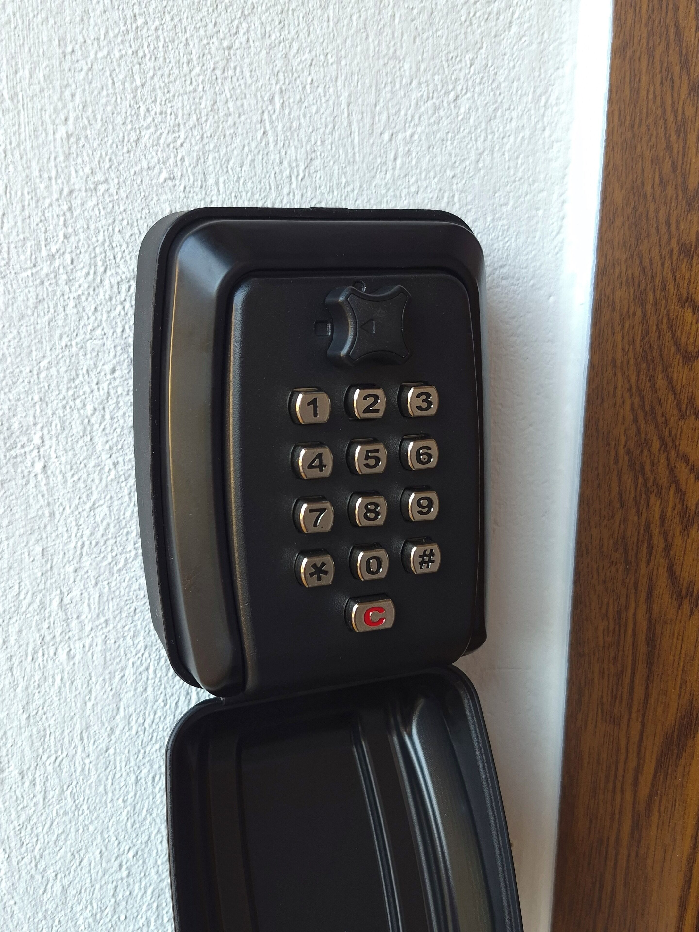 Een zwart telefoon toetsenbord bevestigd aan een muur.