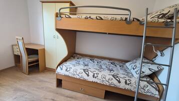 Un lit superposé avec un bureau et une armoire dans une pièce dont le sol est recouvert de parquet.