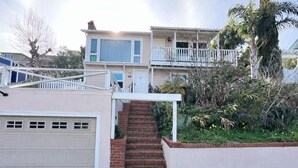 Ein zweistöckiges Haus mit Garage, einer überdachten Veranda und einem kleinen Garten mit verschiedenen Pflanzen und Blumen.