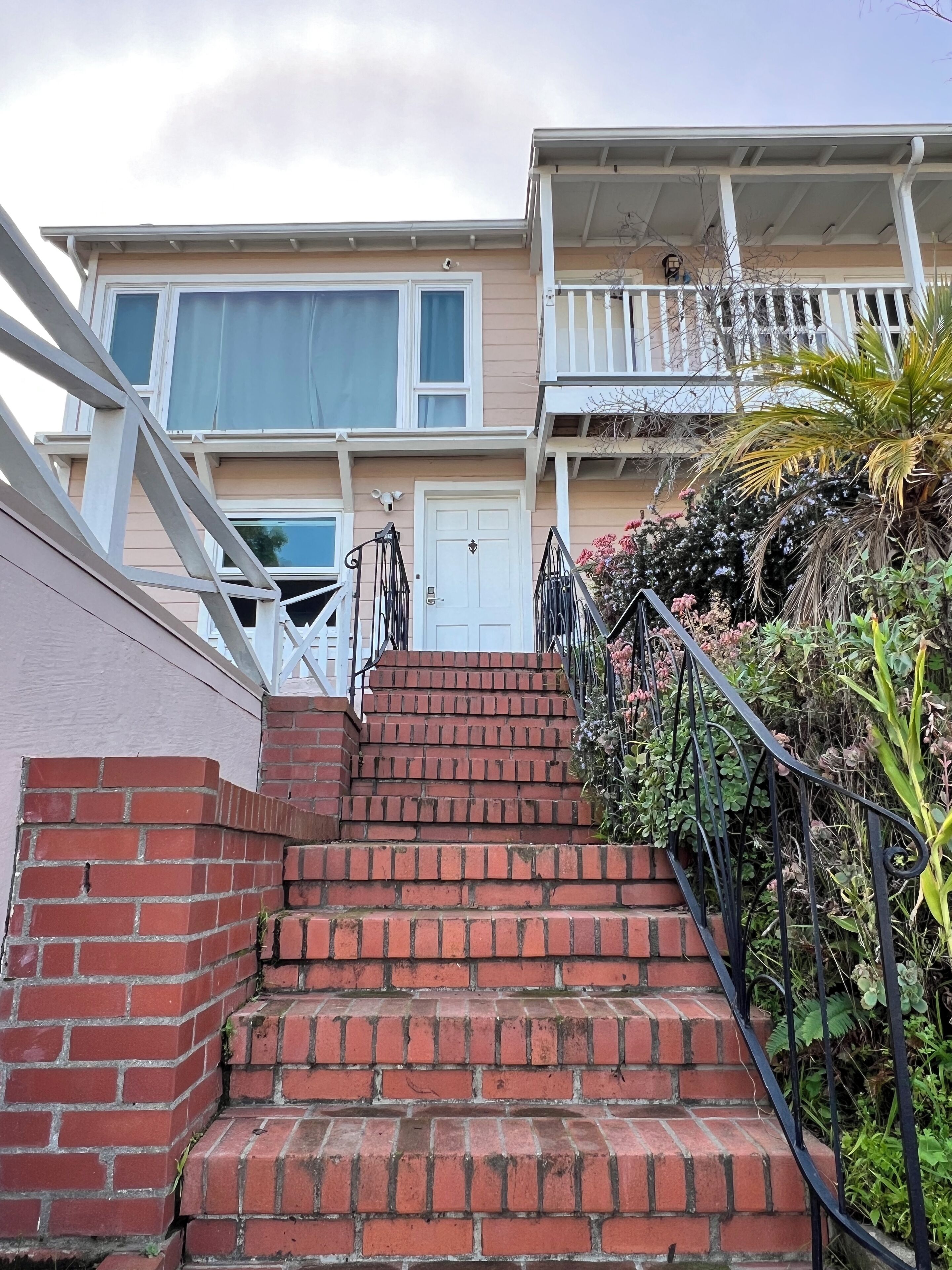 A multi-story residential building with a brick staircase leading to a white door.