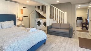 Ein Schlafzimmer mit einem Bett, einer Waschmaschine, einem Sofa und einer Treppe, die zur Küche führt.