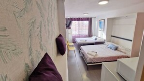 Une chambre d’hôtel avec deux lits, un bureau, un four à micro-ondes et une fenêtre avec des rideaux.