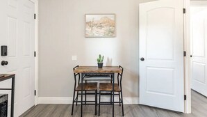 Un coin repas avec une table en bois et deux chaises, une plante en pot et un tableau accroché au mur.