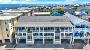 A multi-story hotel with balconies, a covered front porch, and a view of the ocean. - Easy Coastal Living Meets Relaxed Island Comfort | Heated Pool Access (Tybee Island)