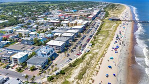A coastal town with a long beach, a pier, and a row of buildings along the shore. - Easy Coastal Living Meets Relaxed Island Comfort | Heated Pool Access (Tybee Island)