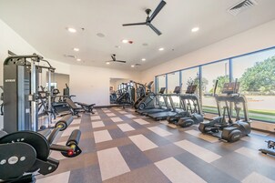 A gym with exercise equipment, a ceiling fan, and large windows.