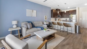 Een moderne woonkamer met een bank, salontafel en barstoelen.