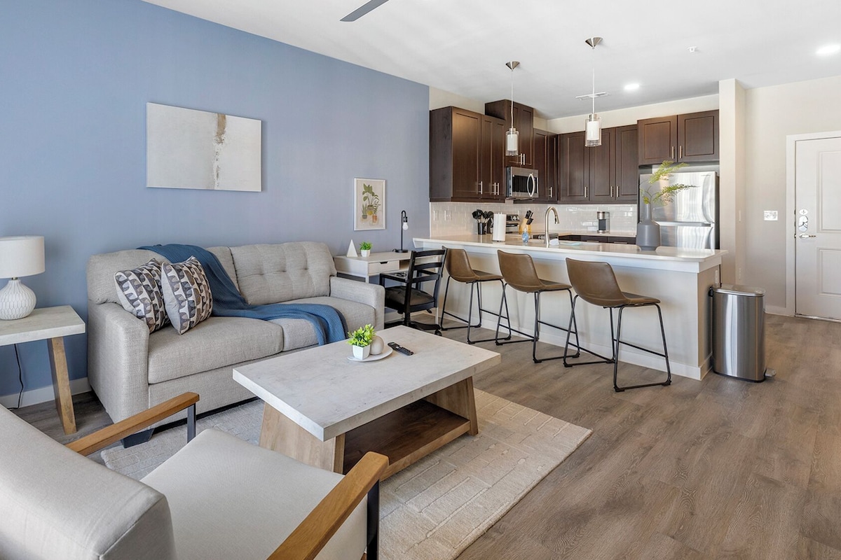 A modern living room with a sofa, coffee table, and bar stools.
