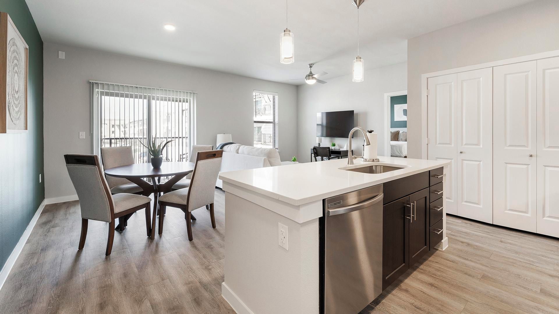 A modern kitchen with a central island, stainless steel appliances, and a dining area with chairs and a table.