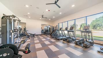 A gym with exercise equipment, a ceiling fan, and large windows.