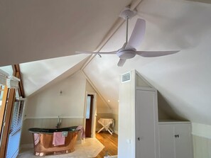 A room with a ceiling fan, a bathtub, and a white cabinet.
