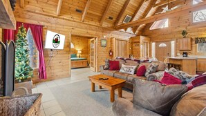 Interior acogedor de una cabaña con paredes de madera, chimenea, comedor y un árbol de Navidad.