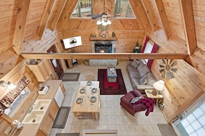 A wooden cabin interior with a dining area, fireplace, sofa, and a ceiling fan. - Little Bear Cabin • Hot Tub • Near Thunder Ridge • Sleeps 6 (Ridgedale)