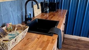 A kitchen with wooden cabinets, a black sink, and a countertop with a basket of items.