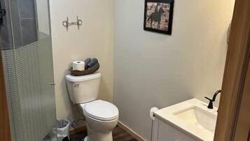 Un baño pequeño con inodoro, cabina de ducha y lavabo.
