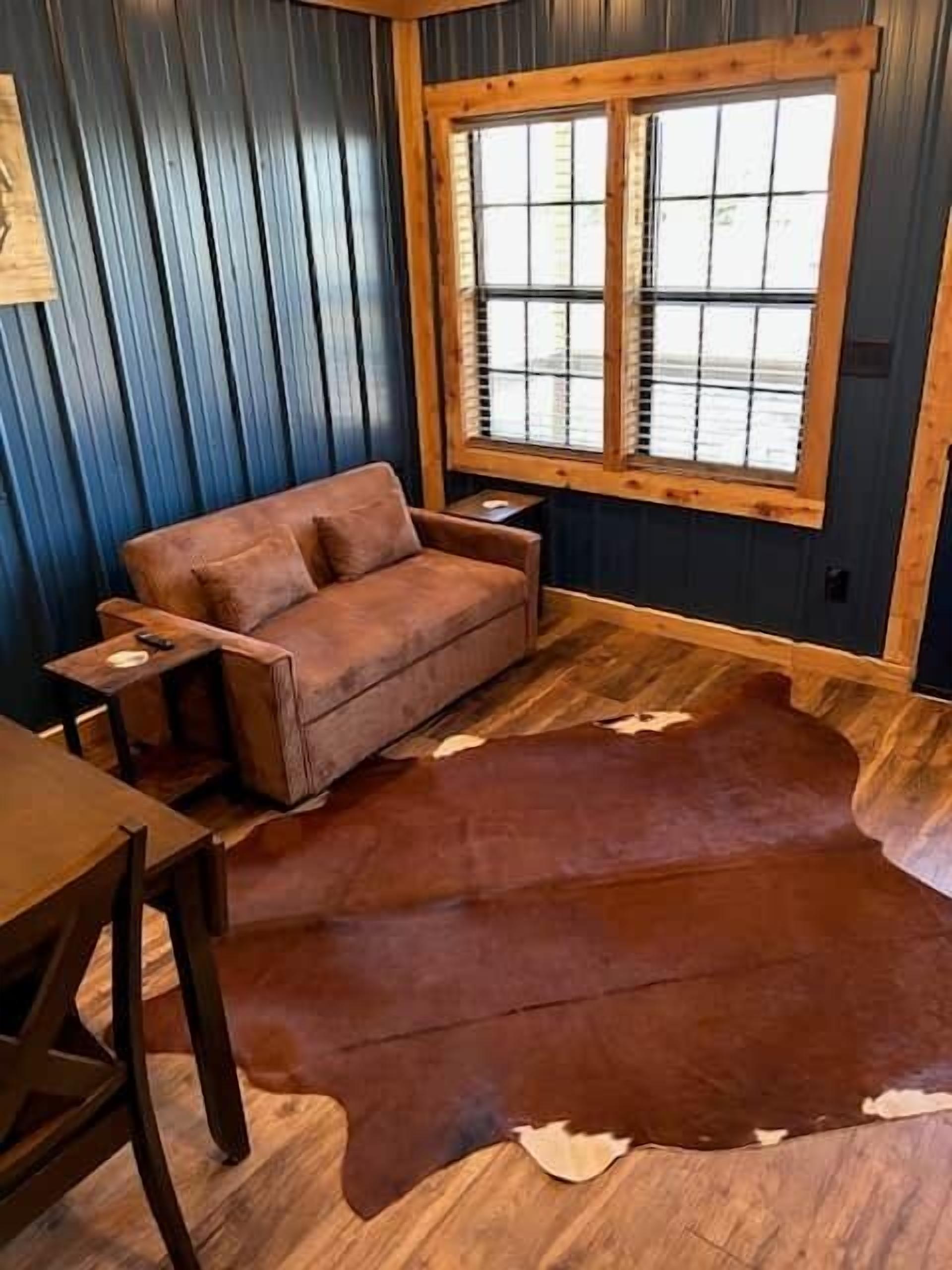 Una habitación con sofá de cuero marrón, mesa de madera y un tapete grande de cuero marrón.