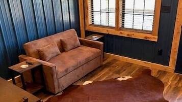 Una habitación con sofá de cuero marrón, mesa de madera y un tapete grande de cuero marrón.