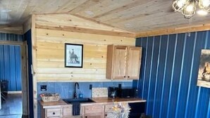 A rustic kitchen with wooden cabinets, a dining table, and a ceiling fan.