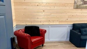 A room with wooden panel walls, a red leather sofa, a black armchair, and a dark sofa. - Jackrabbit on Plumb Ave (Tribune)