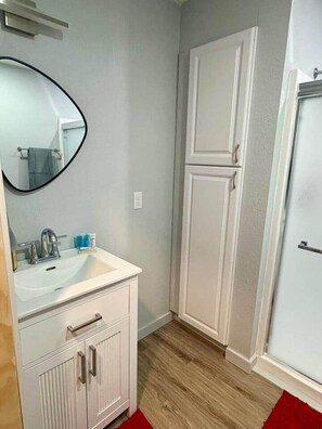 A bathroom with a sink, mirror, and cabinets.