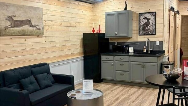 A compact living space with a kitchenette, a sofa, a dining table, and a ceiling fan. - Jackrabbit on Plumb Ave (Tribune)