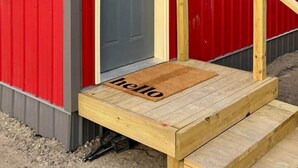A red building with a grey door, a wooden ramp, and a 'hello' mat. - Jackrabbit on Plumb Ave (Tribune)