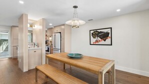 A modern kitchen with wooden cabinets, a dining table with benches, and a pendant light. - Renovated, Stunning Marsh Views,  2BR condo on Amelia Island Plantation (Fernandina Beach)
