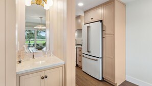 A kitchen with a large white refrigerator, wooden cabinets, a marble countertop, and a pendant light. - Renovated, Stunning Marsh Views,  2BR condo on Amelia Island Plantation (Fernandina Beach)