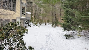 Una casa con terraza y jardín cubierto de nieve.