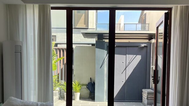 Una sala de estar moderna con un sofá, una mesa de centro y un ventanal corredero que da a un patio.