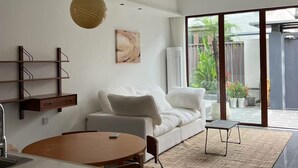Una sala de estar moderna con un sofá blanco, una mesa de comedor y una zona de cocina.