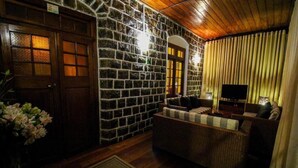 Ein gemütliches Wohnzimmer mit einer Steinwand, Holzbalkendecke und einem Fernseher.
