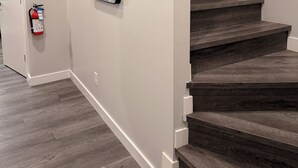 Un escalier avec des marches en bois foncé et des murs blancs.