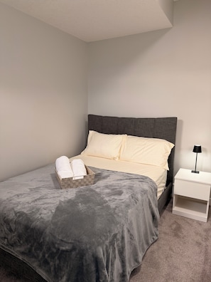 Un dormitorio con cama, mesita de noche y velador.