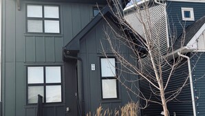 Un immeuble de deux étages, à l’extérieur sombre, avec le numéro « 99 » bien visible sur la façade et un petit arbre dans le jardin.