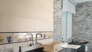 Eine moderne Küche mit schwarzer Arbeitsplatte, weißen Schränken, einer Edelstahlspüle und einer gefliesten Spritzschutzwand.