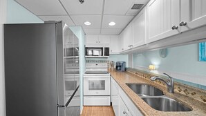 Una cucina moderna con elettrodomestici in acciaio inossidabile, mobili bianchi e un piano di lavoro in granito.