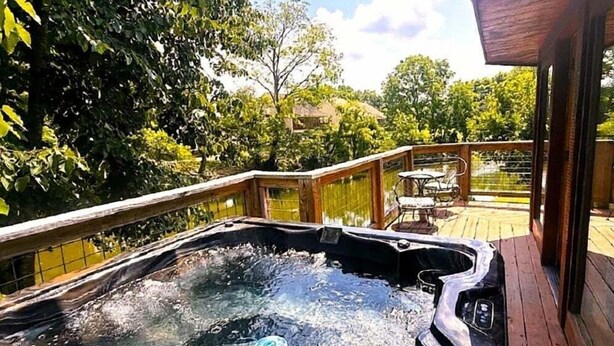 A hot tub on a wooden deck with a view of a house and trees in the background. - Skinny Dippin: Free Tickets, Pet Friendly, Creek (Pigeon Forge)