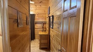 A narrow wooden hallway with a wooden bench and a small table, flanked by wooden doors and walls. - Skinny Dippin: Free Tickets, Pet Friendly, Creek (Pigeon Forge)
