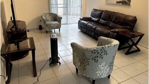 Ein Wohnzimmer mit Klavier, einer Couch, zwei Sesseln und einem Couchtisch.