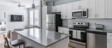 A modern kitchen with stainless steel appliances, a central island, and a dining area with a TV.