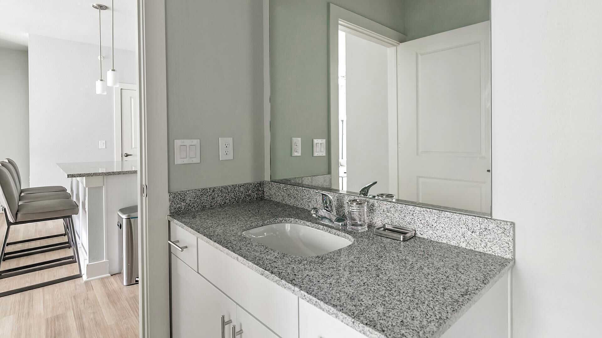 Een moderne badkamer met een granieten aanrechtblad, een wastafel en een spiegel.