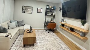 A modern living room with a sofa, coffee table, TV, bookshelf, and decorative items. - Maranatha Enjoyable 1-bedroom apartment with AC in charming Falls Church (Falls Church)