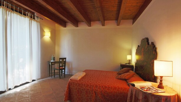 A bedroom with a bed, a table with a lamp, a chair, and a nightstand. - Holiday Home With Pool Near Assisi (Assisi)