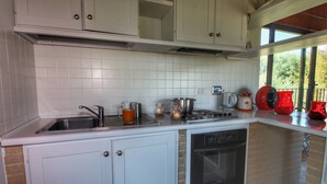 A kitchen with white cabinets, a stainless steel sink, a built-in oven, and a window with a view of trees. - Holiday Home With Pool Near Assisi (Assisi)