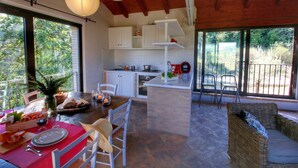 A dining area with a table set for two, a kitchen in the background, and a view of the outdoors. - Holiday Home With Pool Near Assisi (Assisi)