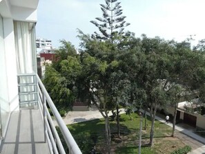 Ein Balkon mit Blick auf einen Innenhof mit Bäumen und einem Gebäude im Hintergrund.