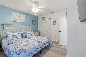 A bedroom with a bed, a ceiling fan, a wardrobe, and a door. - Very clean modern style all new remodel with pools and lots of amenities! PCB (Panama City Beach)